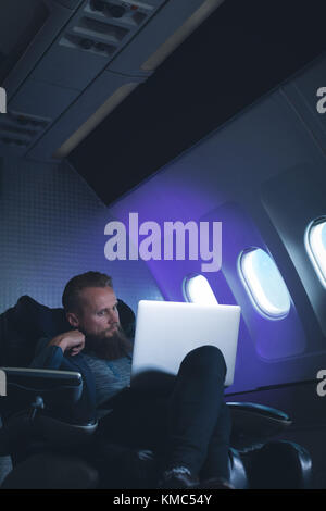 Businessman using laptop in airplane Stock Photo