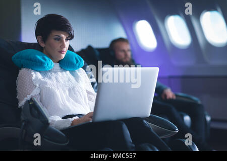 Female executive using laptop in airplane Stock Photo
