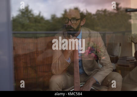 Thoughtful man in full suit sitting on chair Stock Photo