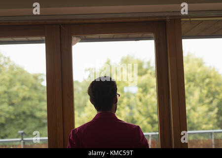 Man in suited looking through window Stock Photo