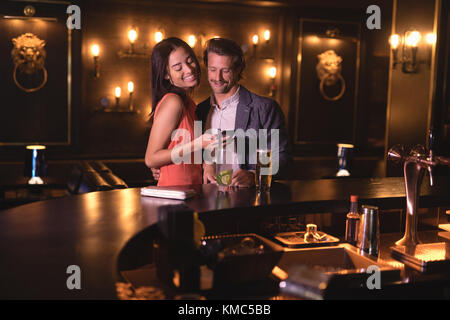 Couple using mobile phone at counter Stock Photo