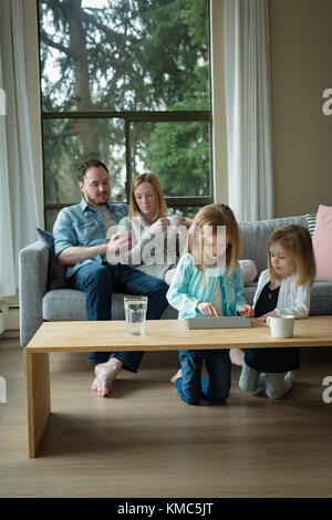 Parents using mobile phone while children using digital tablet Stock Photo