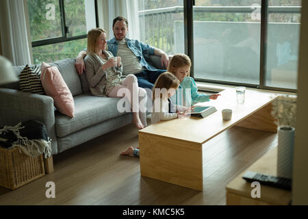Parents interacting while children using digital tablet in living room Stock Photo