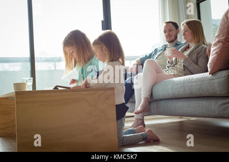 Parents interacting while children using digital tablet in living room Stock Photo