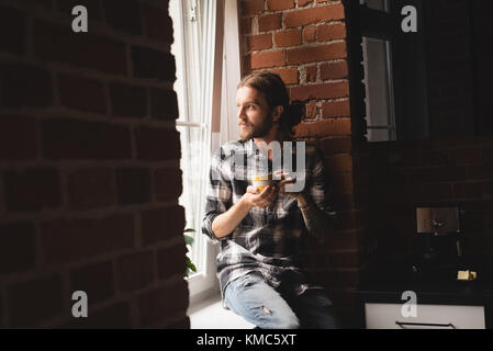 Thoughtful man having coffee near window Stock Photo
