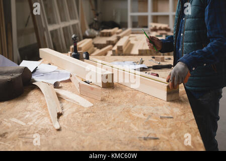 Carpenter measuring wooden slab with measuring tape Stock Photo