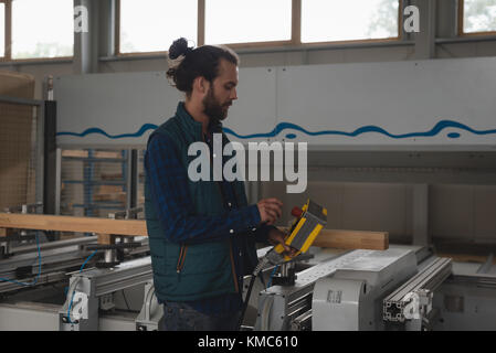 Carpenter using electric machine while working in workshop Stock Photo