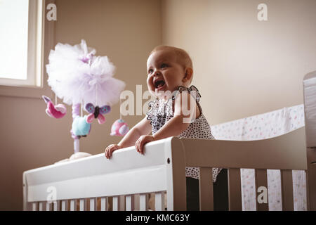 Cute girl standing in cot Stock Photo