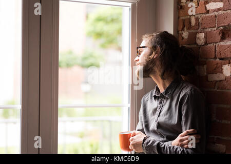 Man looking through window while having coffee Stock Photo