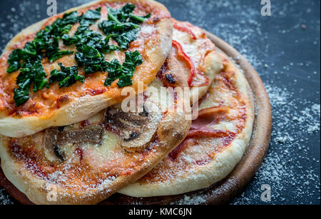 Mini pizzas with various toppings on the wooden board Stock Photo