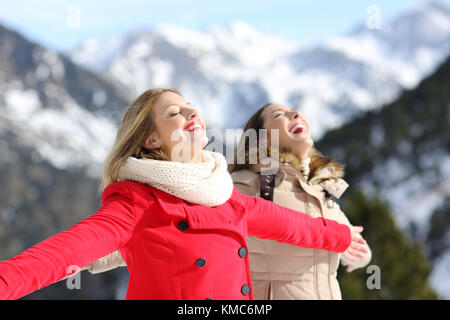 Two happy friends breathing fresh air in winter in a snowy mountain