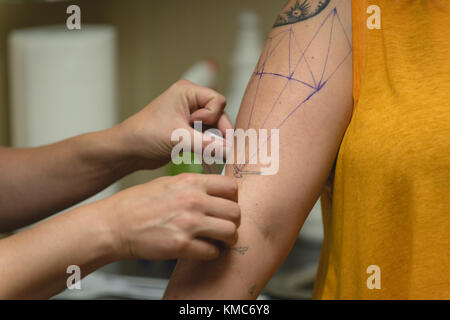 Professional tattoo artist makes a tattoo on a womans hand in tattoo studio Stock Photo