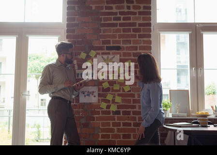 Executives discussing over sticky notes Stock Photo