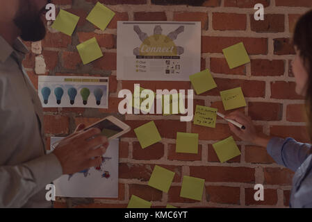 Executives discussing over sticky notes Stock Photo