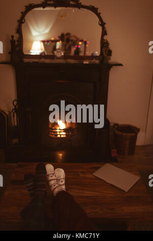 Couple feet in knitted woolen socks warming near burning fireplace
