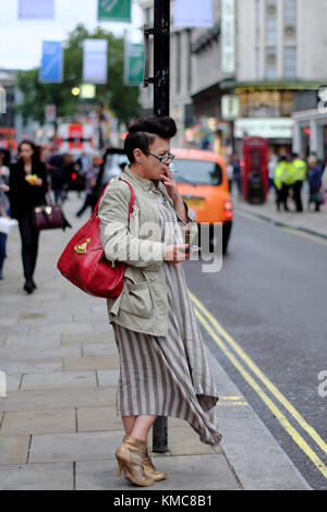 woman leaning against sign post and smoking a cigarette in London, England, UK Stock Photo