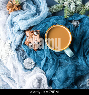 Cream cheese brownies with cookies on blue and mug of coffee and milk. Winter treat square chocolate bars. Holiday background with fir tree branches a Stock Photo