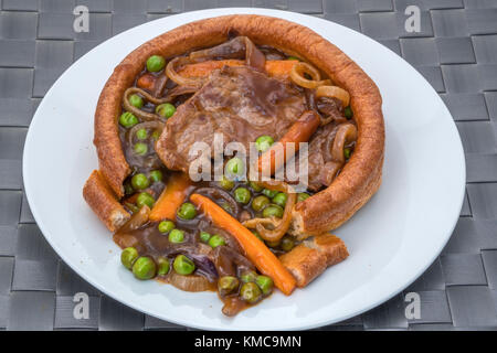 A filled Yorkshire pudding with sliced beef, vegetables and a thick gravy. Stock Photo