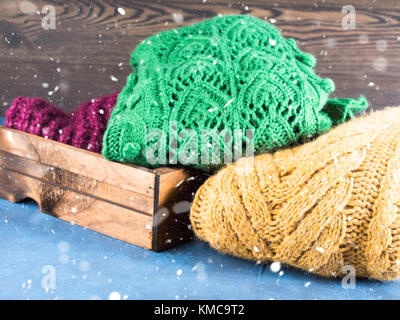 Winter womans woolen sweaters. Knitted girls clothing. Colorful pullovers on wooden background. Cozy clothes for the season. Stock Photo