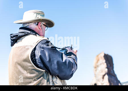 Perce, Canada - June 6, 2017: Professional man photographer taking picture on boat by Rocher Perce rock in Gaspe Peninsula, Quebec, Gaspesie region Stock Photo