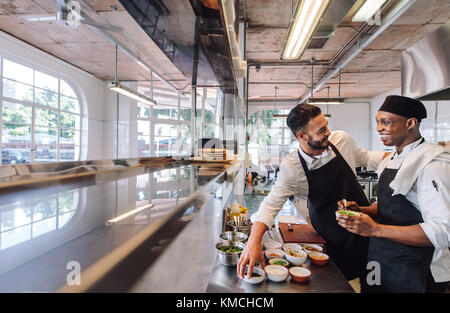 Professional chefs working in restaurant kitchen. Smiling chefs cooking food at commercial kitchen. Stock Photo