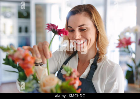 Female florist arranging flowers. Woman flower shop owner placing flowers in a bouquet. Stock Photo