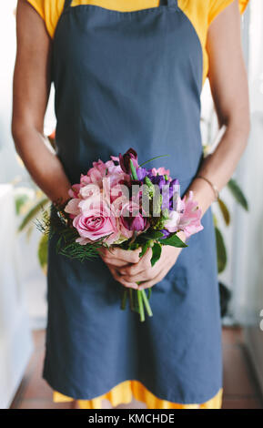 Cropped shot of woman holding mixed flower bouquet in hand. Florist with fresh flowers at flower shop. Stock Photo