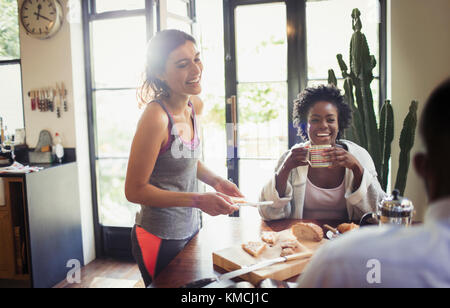 Smiling friends enjoying breakfast at kitchen table Stock Photo