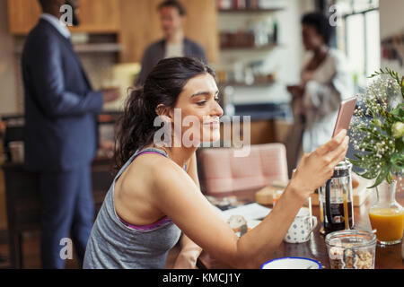Young woman texting with smart phone at breakfast table Stock Photo