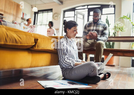 Female freelancer working at laptop on living room floor Stock Photo