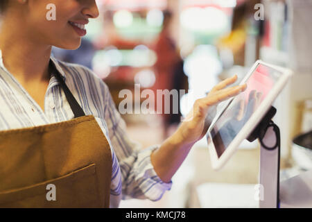 Female cashier using touch screen cash register in grocery store Stock Photo