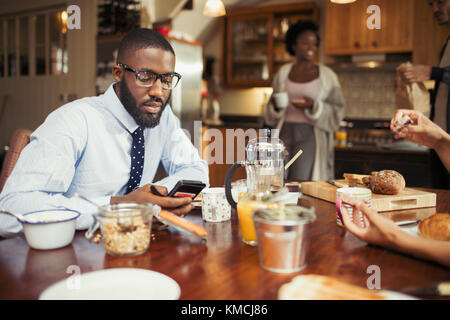 Businessman texting with smart phone at breakfast table Stock Photo