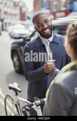 Smiling businessman with bicycle shaking hands with woman on urban street Stock Photo