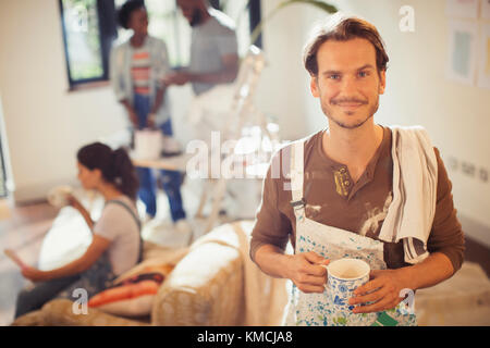 Portrait smiling man drinking coffee and painting living room Stock Photo