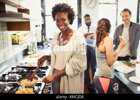 Portrait smiling woman cooking scrambled eggs at stove in kitchen Stock Photo