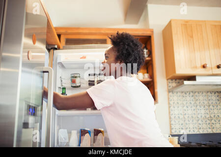 Woman reaching into refrigerator in kitchen Stock Photo