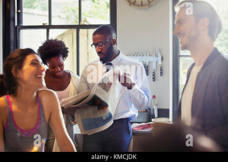 Friend roommates talking and reading newspaper in morning kitchen Stock Photo