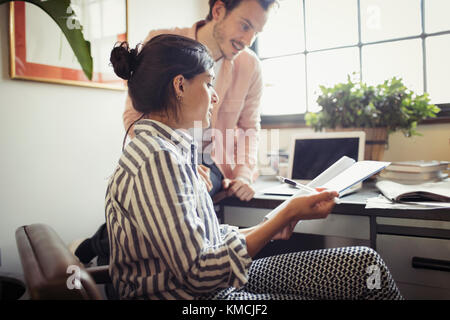 Businessman and businesswoman reviewing and discussing paperwork in office Stock Photo