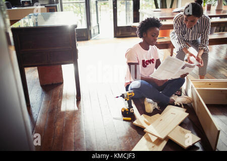 Women reading instructions, assembling furniture Stock Photo