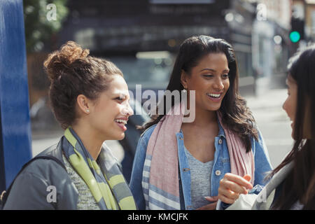 Smiling female friends talking on urban street Stock Photo