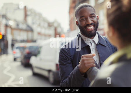 Smiling businessman shaking hands with colleague on urban street Stock Photo