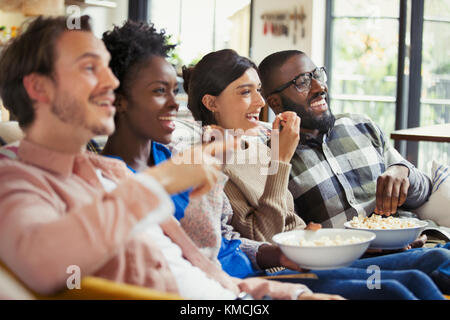 Smiling couples watching movie, eating popcorn Stock Photo