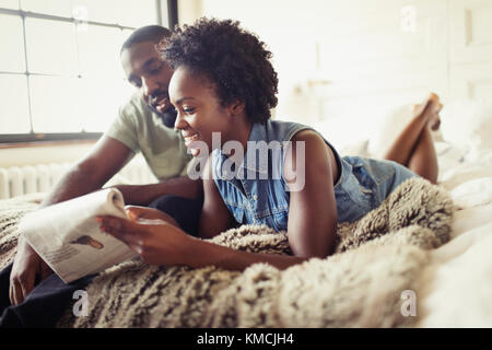 Couple relaxing, reading newspaper on bed Stock Photo