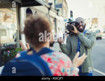 Young man with video camera videoing woman on street Stock Photo