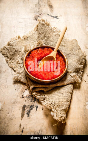 Red caviar in a cup on old fabric. On wooden background. Stock Photo