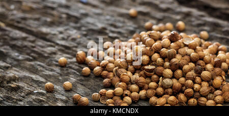 Dried coriander seeds in a pile set on old wooden surface. Closeup view and copyspace for text. Stock Photo