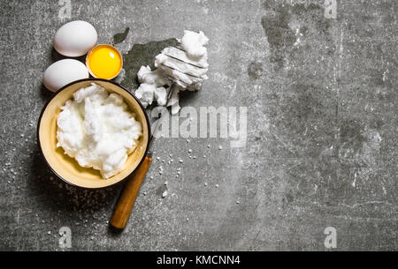 Whipped eggs in a bowl with a whisk. On a stone background. Free space for text . Top view Stock Photo