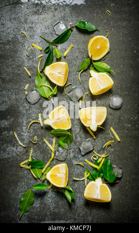 Slices of lemon, ice, leaves on the stone table.  Top view Stock Photo
