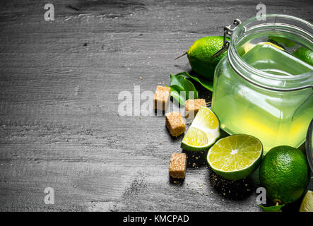 Lime background. The juice from the limes, sugar and slices of lime. On a black wooden background. Free space for text . Stock Photo