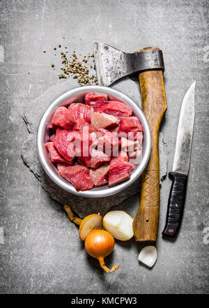 Chopped raw meat with an axe, cutting knife and spices. On the stone table. Top view Stock Photo